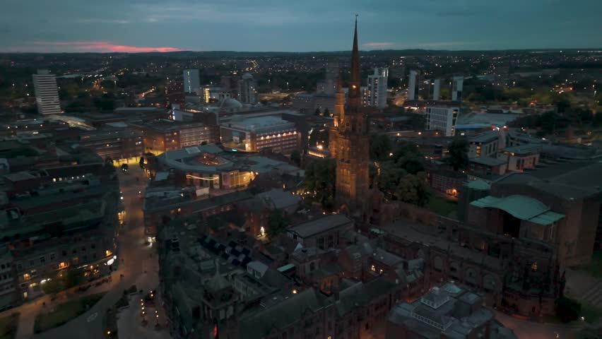 Aerial view of illuminated Coventry cathedral and cityscape at dusk, showcasing cultural landmarks and city lights