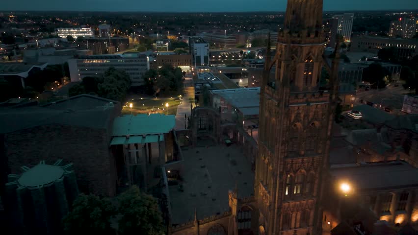 Aerial night view of Coventry city, showcasing the illuminated cathedral and surrounding buildings. Capturing the cultural essence