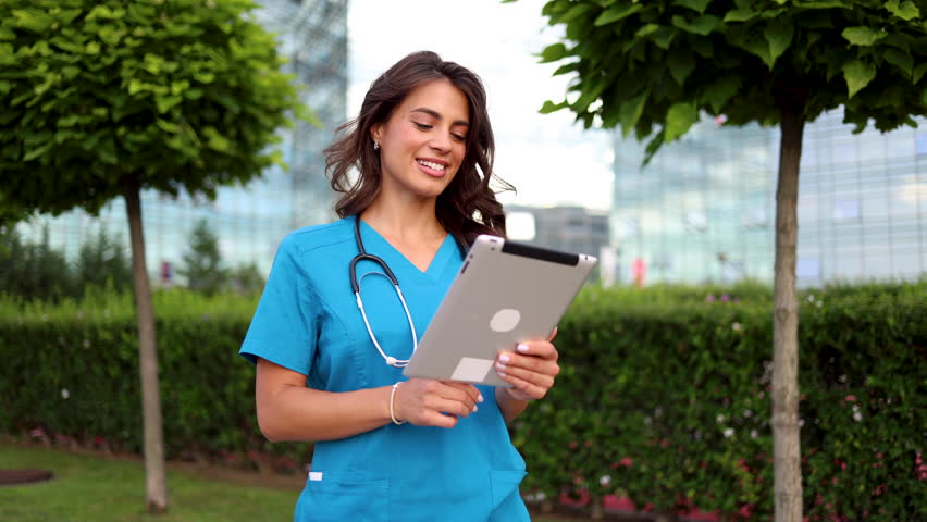 Beautiful doctor using tablet on the street