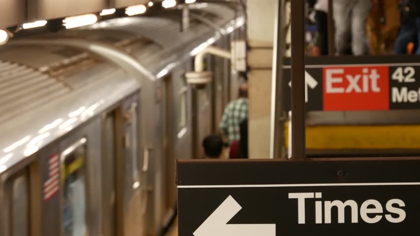 New York subway station interior, underground metropolitan platform. United States public metro transportation. Passenger railway traffic. Text sign: Times Square, Grand Central, 42. People and train.