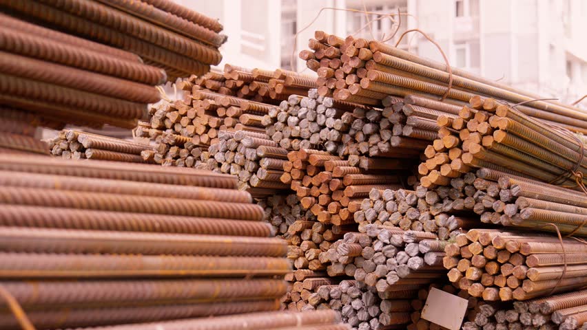 Construction steel reinforcement on construction site. Deformed bars for reinforced concrete metal surfaces Steel bars lying on ground, ready for recycling in industrial area.