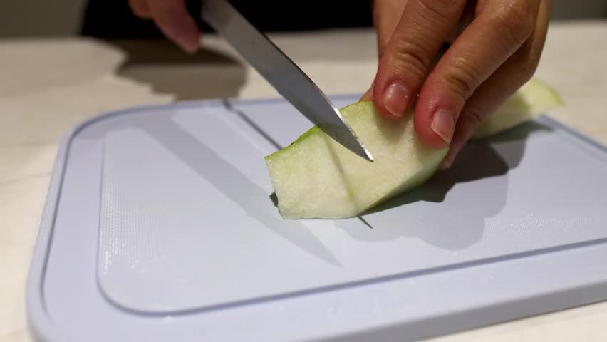 Slicing a pear with a knife on a board
