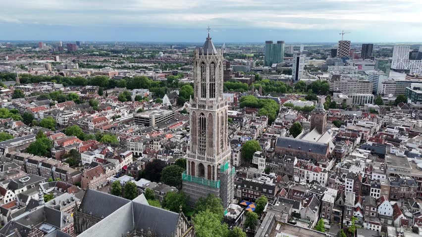 A stunning aerial drone shot of the magnificent Dom Tower in Utrecht, Netherlands, highlighting its grandeur and the charming city surrounding it.