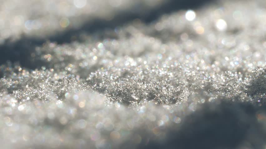 Close-up view of snow crystals that are glistening in the light. Each crystal is