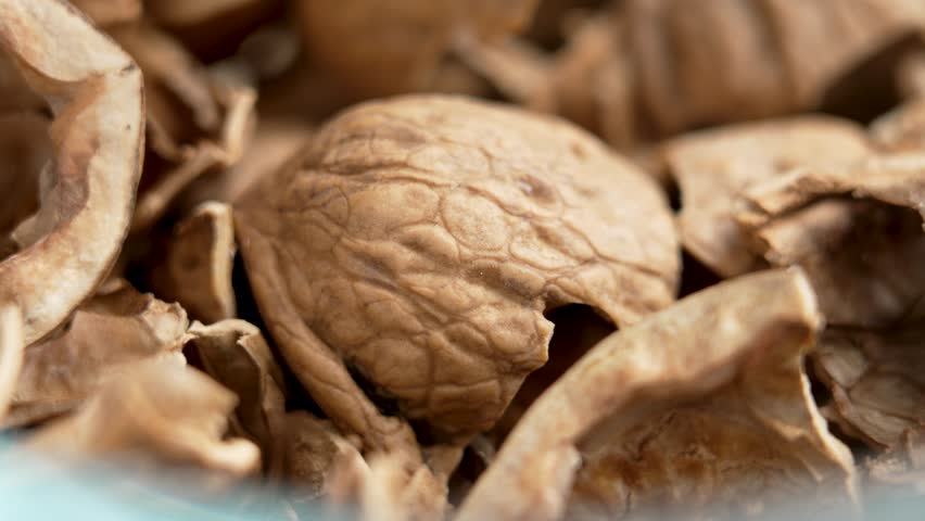 Broken crushed cracked organic empty walnut shells as leftovers and kitchen waste after eating in a glass bowl. Macro shot. Rotation. Healthy food concept