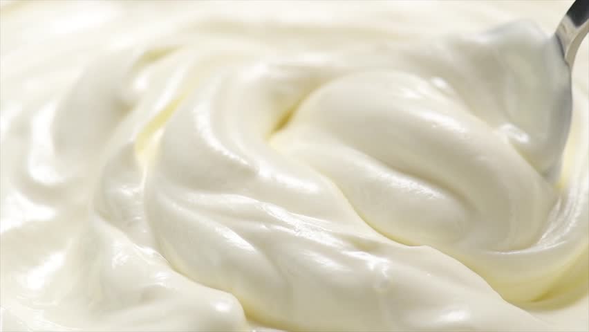 Sour cream or greek yogurt scooping  with a spoon, swirl, rotating texture, White cream, yoghurt background, close up. Dairy product. Delicious organic creamy yogurt. Tasty Milk cream macro shot