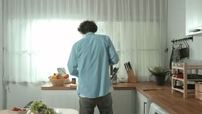 Happy father move to music while cooking food and prepare lunch at modern kitchen. Active dad dancing to song while making healthy food or salad surrounded with vegetable and kitchenware. Pedagogy. - Powered by Shutterstock - Get 15% off with code: PIKWIZARD15