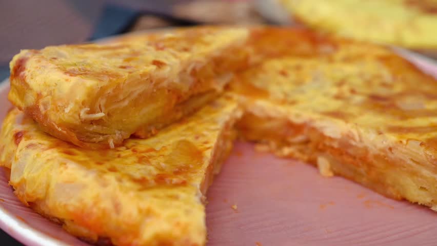 Man Cutting Homemade Spanish omelette (tortilla de patatas) with a knife at the center of a Spanish family’s table