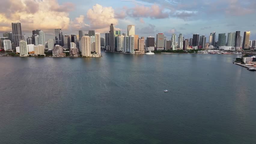 Drone approaching shot of downtown Skyline in Miami during golden sunrise. Flight over Miami River with skyscrapers on shoreline. Panorama shot.
