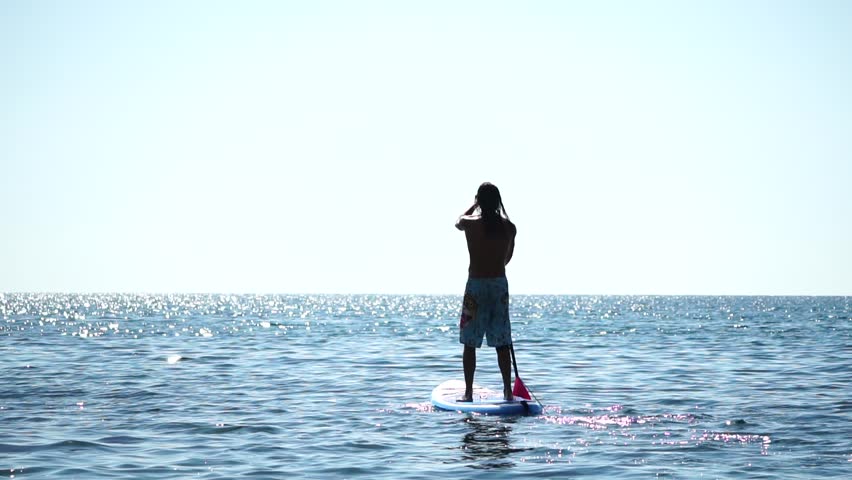 Man Sup Sea. Strong athletic man learns to paddle sup standing on board in open sea ocean on sunny day. Summer holiday vacation and travel concept. Aerial view. Slow motion