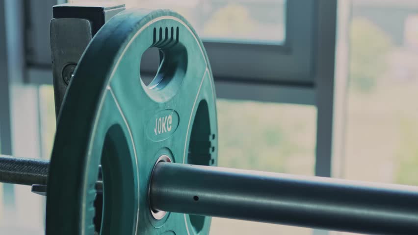 Powerlifting workout. Athlete adding weight plates on barbell before exercising at gym, close up