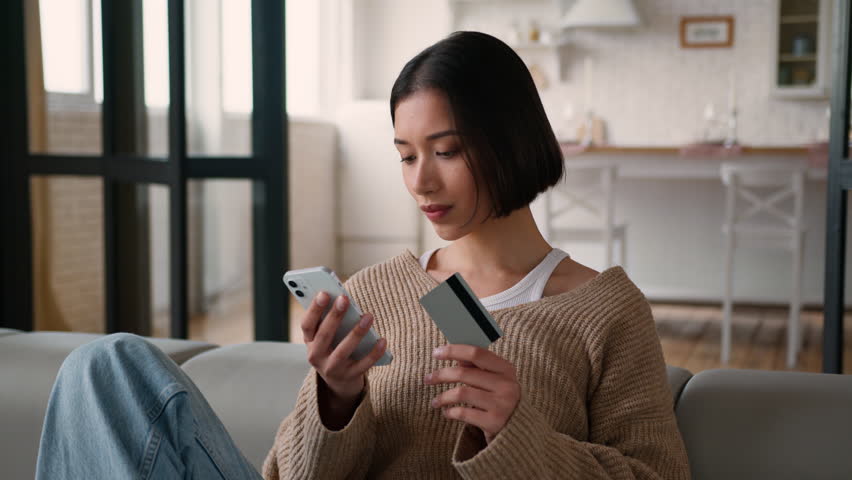 Caucasian hispanic woman thoughtful pensive girl female homeowner buyer shopper shopping online internet store purchase think choose order delivery at home buy pay credit card mobile phone bank app