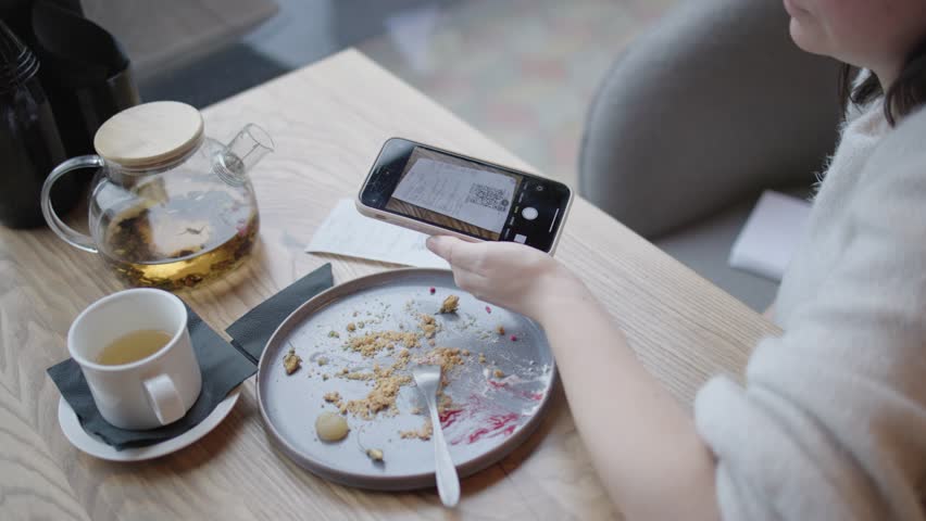 Sitting at cafe table person paying for meal using QR code contactless payment. Contactless payment with few taps on mobile phone complete transaction online contactless payment in restaurants