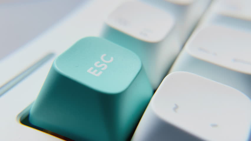 Close-Up of Escape Key Being Pressed. Close-up view of Escape key in white keyboard pressed in different ways while a red led illuminates. 

