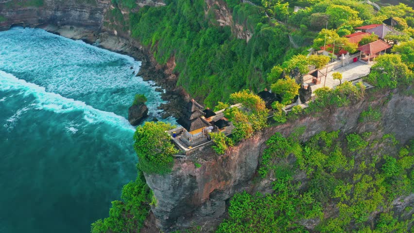 Bali's Most Iconic Landmark and popular tourist attraction Uluwatu Temple one of six key Bali temple perched on top mountain cliff on background amazing nature Bali, Indonesia. 4K Aerial view