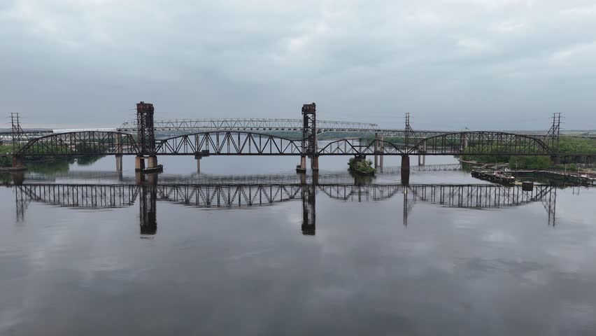 Aerial View of a Vertical Lift Railroad Bridge and the Betsy Ross Bridge Reflecting off the Still Waters of the Delaware River 