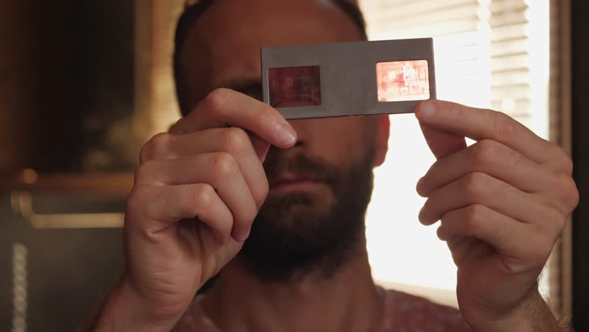 Adult man looks at old photo slides close-up