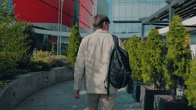 back view of a asiatic male student walking, wearing a backpack, savors the peaceful ambiance of the university garden, his focused gaze on the pages of his textbooks. - Powered by Shutterstock - Get 15% off with code: PIKWIZARD15
