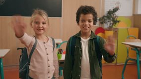 Two smiling happy multiracial diversity children school kids multiethnic little Caucasian girl daughter kid African American boy son child at camera waving hands hello hi greeting studying education - Powered by Shutterstock - Get 15% off with code: PIKWIZARD15