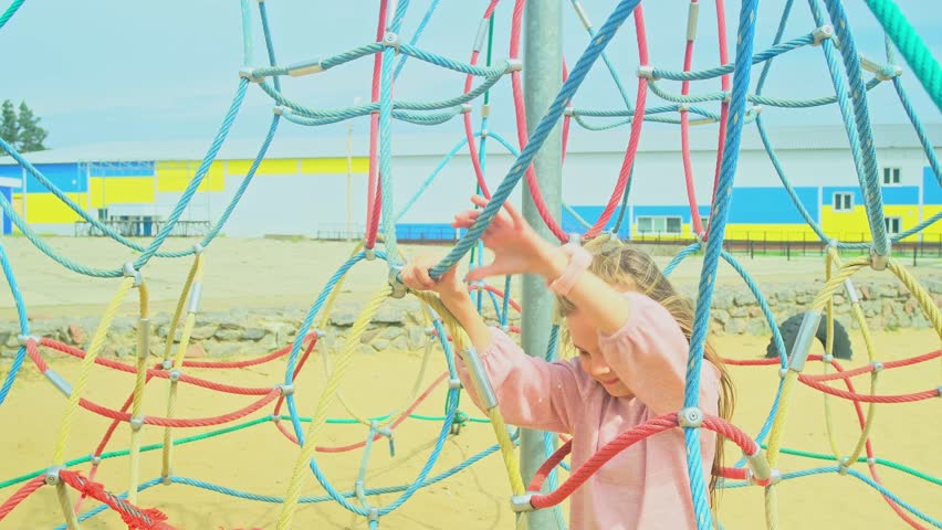 Happy little girl climbing on outdoor playground