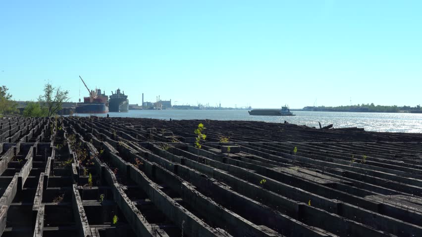 Barge on the River in New Orleans with old wooden dock moorings on shore