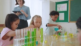 Adorable student learn with teacher in classroom at elementary school. Group of young schoolboy and girl sit on table, study science and doing chemistry experiment with fun activity at kindergarten. - Powered by Shutterstock - Get 15% off with code: PIKWIZARD15