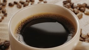 White cup of coffee on a wooden table with coffee beans and rising steam slowly rotates. Nice warm coffee background for your projects. - Powered by Shutterstock - Get 15% off with code: PIKWIZARD15