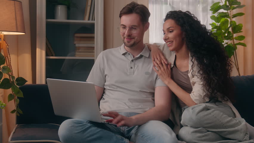 Caucasian man husband boyfriend male guy talking discuss online shopping laptop purchase with Arabian wife Hispanic girlfriend girl woman female at home couple family budget buying order delivery talk