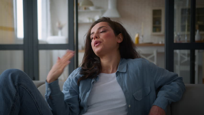 Overheated Caucasian woman on sofa couch wave hand refresh tired cool with arms unhappy sweaty lady girl female suffer of high temperature problem feel sweat at hot living room without air conditioner