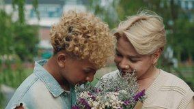 Asian gay couple embraces while smelling a bouquet of wildflowers on a city street. Romantic men enjoy the fresh flowers together on a date, promoting LGBT community visibility and tolerance. - Powered by Shutterstock - Get 15% off with code: PIKWIZARD15