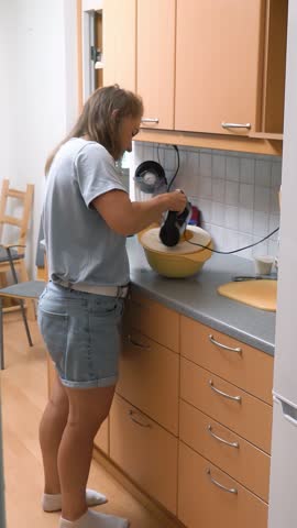 Young woman cooking in the kitchen of her home. Whisk the baking mass for dessert with a mixer.
