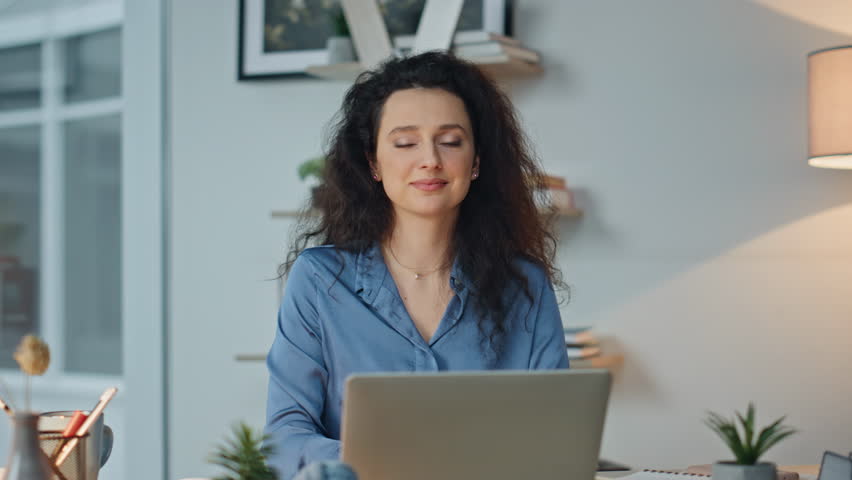Portrait smiling it manager at modern workplace. Successful businesswoman posing at laptop computer. Cheerful professional enjoying work in contemporary office. Brunette employee 