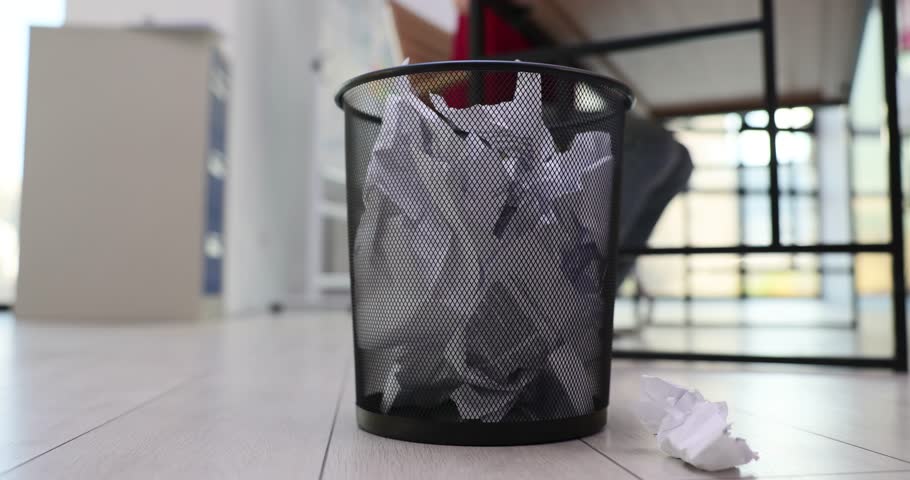 Worker throws papers in rubbish bin with sense of frustration. Demonstration of revisions and rejections as part of working process
