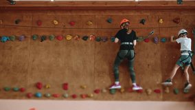 A strong 13s girl struggles with fear of heights during a training session in a rope park. A girl in protective gear moves along the vertical wall of the climbing wall, stage of the obstacle course - Powered by Shutterstock - Get 15% off with code: PIKWIZARD15