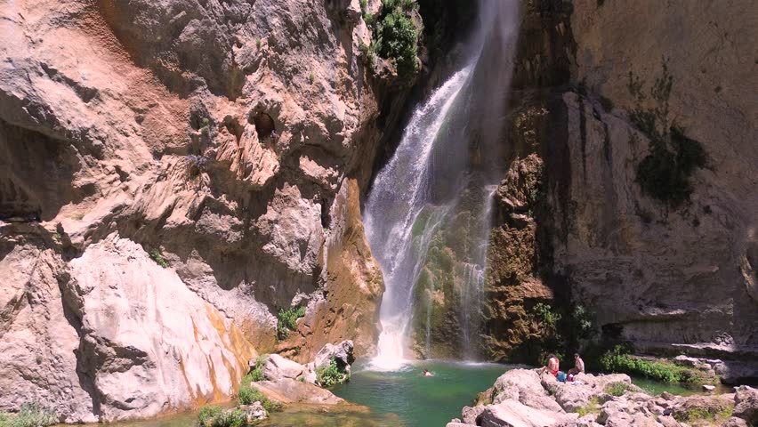 People take a bath under a waterfall during summer aerial drone view