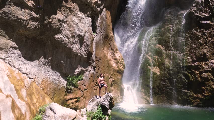 People take a bath under a waterfall during summer aerial drone view