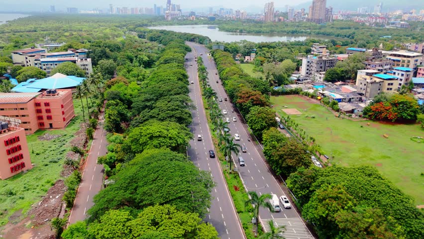 Drone moving up high over city street, Aerial view of highway between sea and lake, Palm beach road navi mumbai, winding expressway, by lush greenery, A large water body on one side, with cityscape