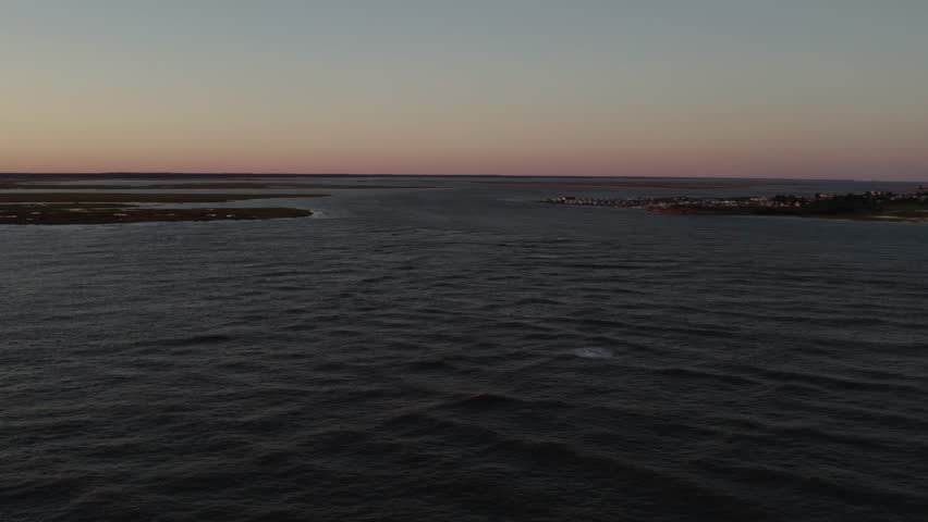 Dusk glow of light spreads across serene peaceful sky in Chincoteague Island Virginia, slow motion