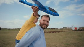 Happy family smiling Caucasian man male father dad carrying piggy back ride whirling little boy son kid playing flying toy airplane plane boys having fun child dream parenting fatherhood village field - Powered by Shutterstock - Get 15% off with code: PIKWIZARD15