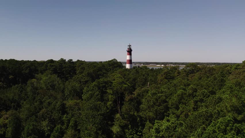 Aerial dolly to red and white banded lighthouse in national wildlife refuge Chincoteague Island Virginia, slow motion