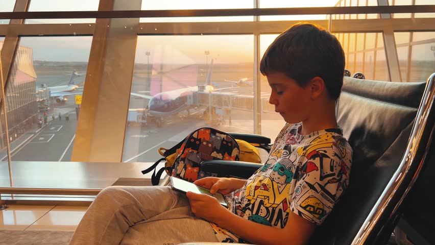 teenager emotionally playing on phone at airport with sunset light