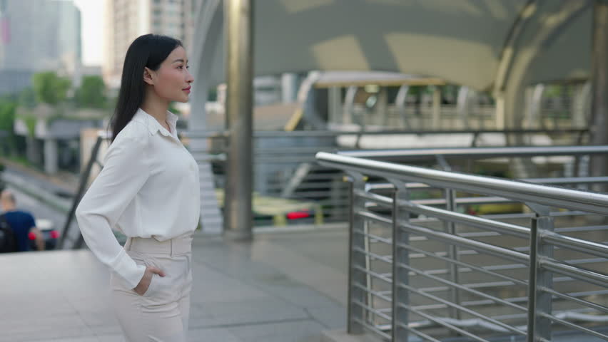 Young Incredible Asian Woman Standing Pose with Hands in Pockets and Smiling at Camera. Portrait of a Beautiful Business Woman on the Street Happy in an Office Outfit. People and Business Concept