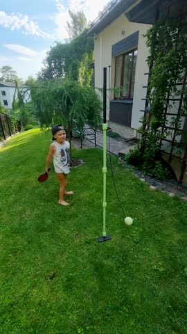 children playing totem tennis outdoors at home backyard
