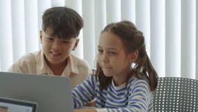 Medium shot of cheerful biracial kids coding on wireless laptop during computer class at desk - Powered by Shutterstock - Get 15% off with code: PIKWIZARD15