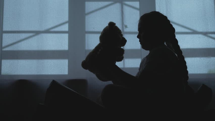 Depressed Kid holds teddy comfort from problems. Kid with teddy bear quiet solace amidst tears. Solace for child facing problems. Depressed Kid finds listener in teddy bear. Child in tough times.