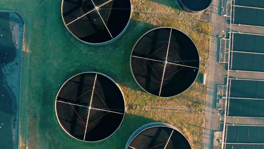 Aerial top down view of sewage treatment plant. Industrial water treatment with round water tanks for sewage recycling from drone view. Waste water management