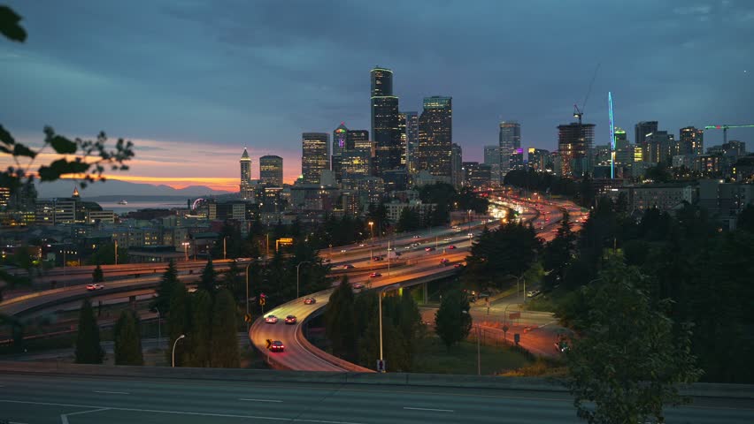 Sunset over the Seattle downtown skyline, with city lights, traffic and moving cars on the I-5 and I-90 freeway interchange. 4K UHD video.
