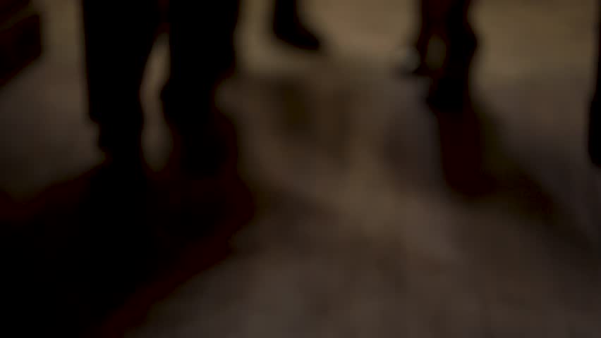 People's feet enter the room. Silhouette of man's and woman's legs entering to the dark room and walking. 