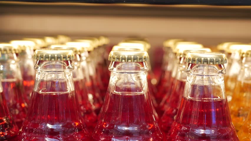 Vintage beverage bottles with colorful caps on bar shelf create a nostalgic retro drinks display