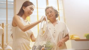 4K Happy Asian family shopping grocery and vegetables at market together. Mother and daughter unpacking vegetables and food in cotton sustainable reusable mesh shopping bag in the kitchen at home. - Powered by Shutterstock - Get 15% off with code: PIKWIZARD15